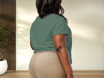 Person wearing a bay green shirt and beige pants in an indoor setting to show back view of tee and fit on a curvy model.