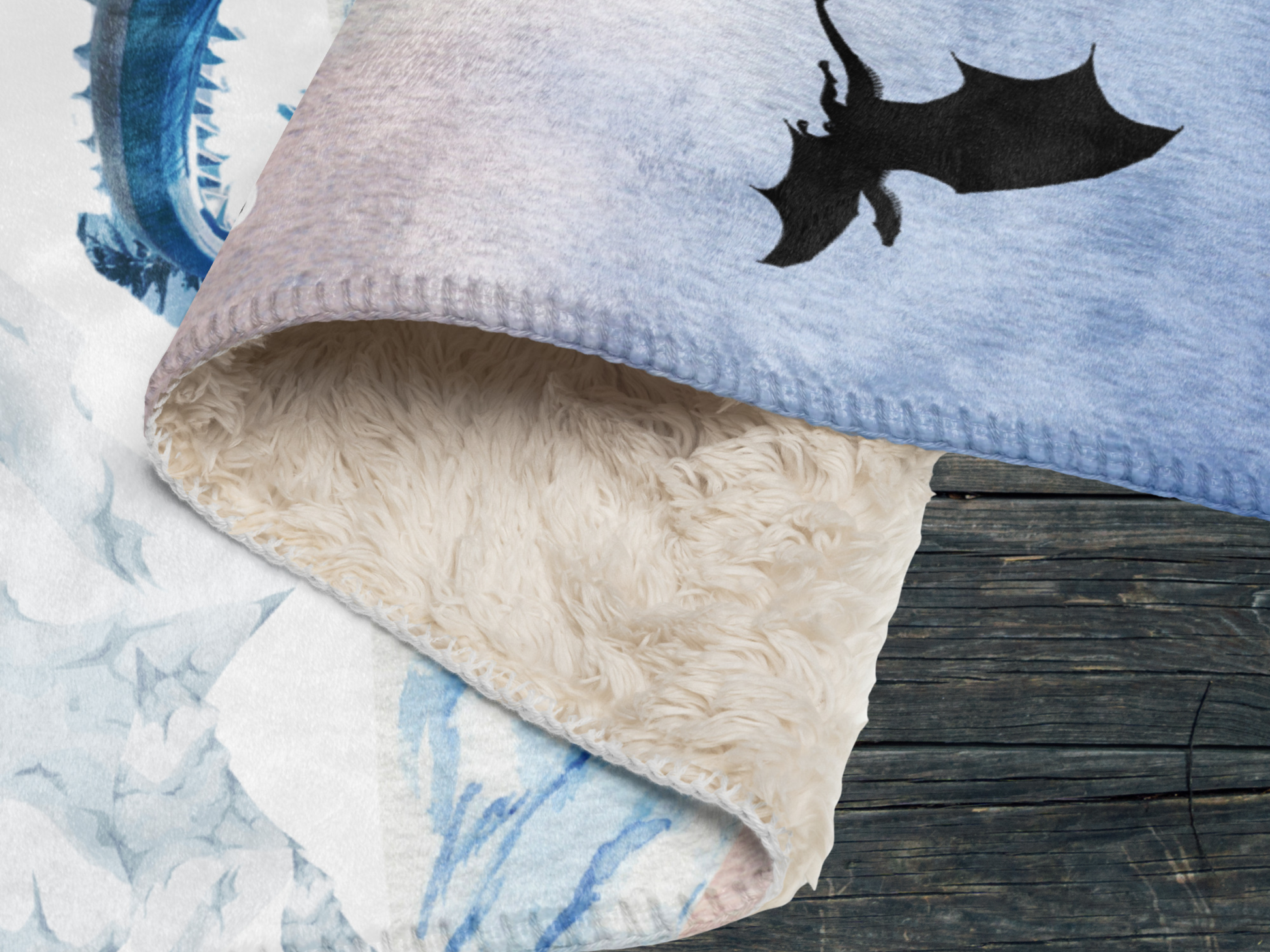Fantasy Ice Dragon Throw blanket folded over to show stitching on edges of blanket, the soft top of the lightweight blanket, and the plush sherpa bottom.