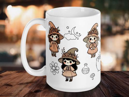 Vintage Whimsigoth Ceramic Witch Coffee Mug. Mug is white with the handle to the left. You can see three chibi kawaii withes with large eyes. Each little witch's hat has a floral crown. Once brunette, one blonde, and one with black hair. Witches are in earth tones and in vintage style dresses and shoes. You can see the outline of a flower, a potion bottle, a mushroom, and a moon with stars.