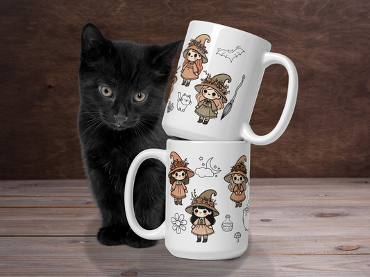 Kawaii Pretty Witch Ceramic Cup. White 15 oz witchy mug is stacked so that you can see both sides of the mug. The top mug has the handle to the right and the bottom mug has the handle to the left. Behind the mugs is a black kitten.