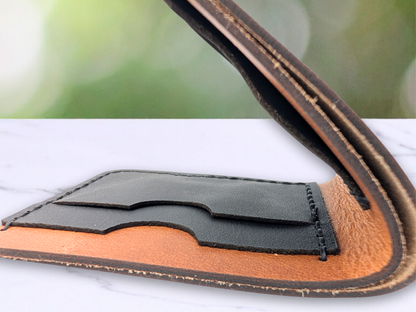 Close up of the folded handmade veg tan wallet. view is of the wallet laying flat looking at the edges of the leather forming the cash compartment. The edges are darkened and you see slightly into the cash compartment to see the raw suede. You can see the tops of two of the black leather card pockets on the interior of the wallet. 