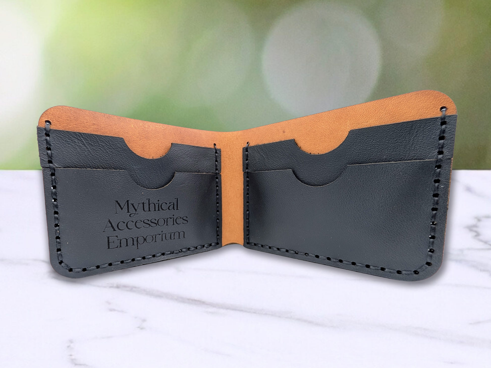 BI fold handmade leather wallet is standing up to see the interior of the wallet. ON the left and right you see two card pockets on each side handsewn together of black pebbled leather for a total of four card pockets. The stitching is done in black. There is a curve at the top of each card pocket to make it easier to pull the cards in and out of the pockets.