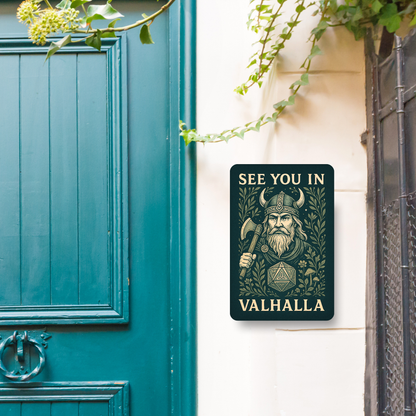 Metal  Wall Poster 8x12 hanging next to a blue front door. Dark green Metal Sign with graphic in light golden browns. Bearded Viking wearing a horned helmet and holding an axe over his shoulder. D20 with symbols instead of numbers below the Viking. Botanical Design surrounding the image with mushrooms, vines, and flowers. At the top of the wall art it says, "See You In". At the bottom of the home decor, "Valhalla".  Wall Art Apartment Decor