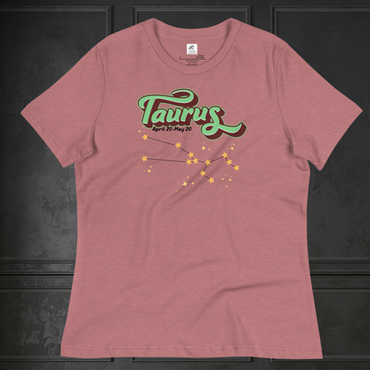 Front view of heather mauve Taurus Tee laying flat on a black surface. You can see the crew neck collar and short sleeves of the t shirt. This Astrology T-Shirt has the word Taurus in large leaf green script shadowed in deep brown for a 3-D effect. Below this it Says April 20-May 20. At the bottom is the star constellation for Taurus with yellow stars connected by a black line and  smaller stars surrounding the constellation. The perfect April or May Birthday Gift for Her or yourself.