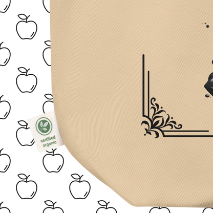 Up close view of front bottom left corner to see certified organic tag Natural Organic Tote Bag Poisoned Apple Enthusiast above a decaying apple sitting in a pool of poison