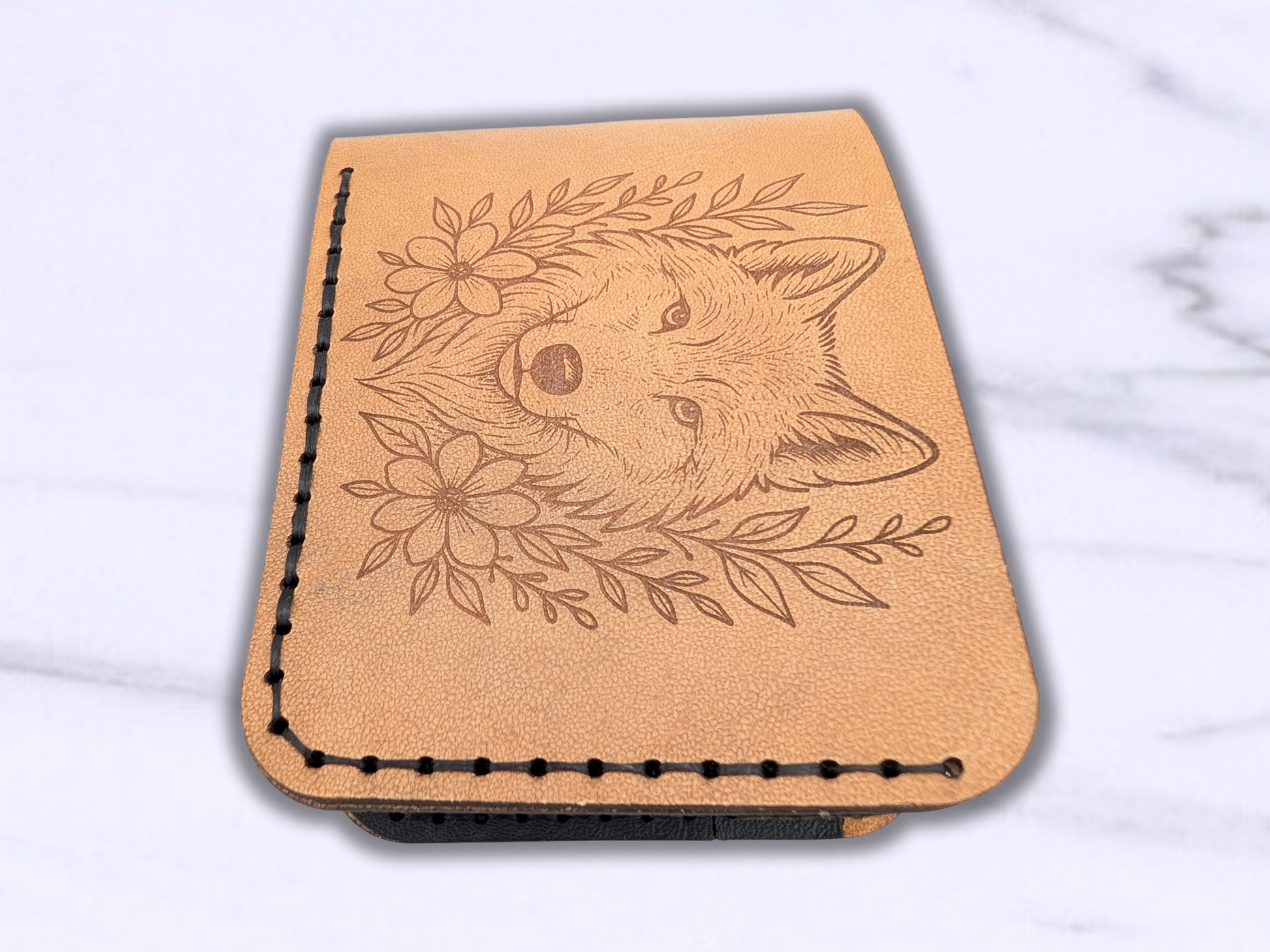 Bi fold veg tan leather wallet, handcrafted, laser engraved wolf head. Wallet is flat with the edge of the wallet that you open to the front of the photo. 