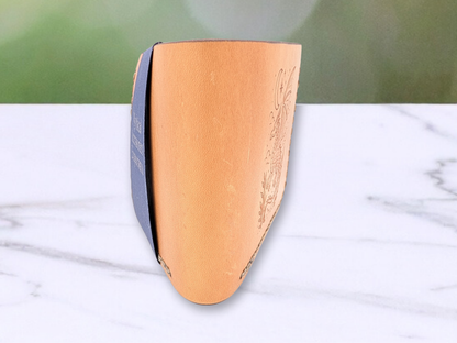 Leather bi fold wallet is standing on its side. You are viewing the wallet from the folded round edge. This image gives you a feel for the richness of the leather and how it folds in half. You get a glimpse of the front and the back.