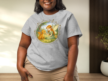 Curvy model wearing an athletic grey tee with a fantasy graphic. Circle shaped graphic is framed in gold rose vines. A fairy kneels in a forest meadow petting a reddish baby dragon. Fairy is wearing a long green dress and has auburn hair. Insect like wings. 