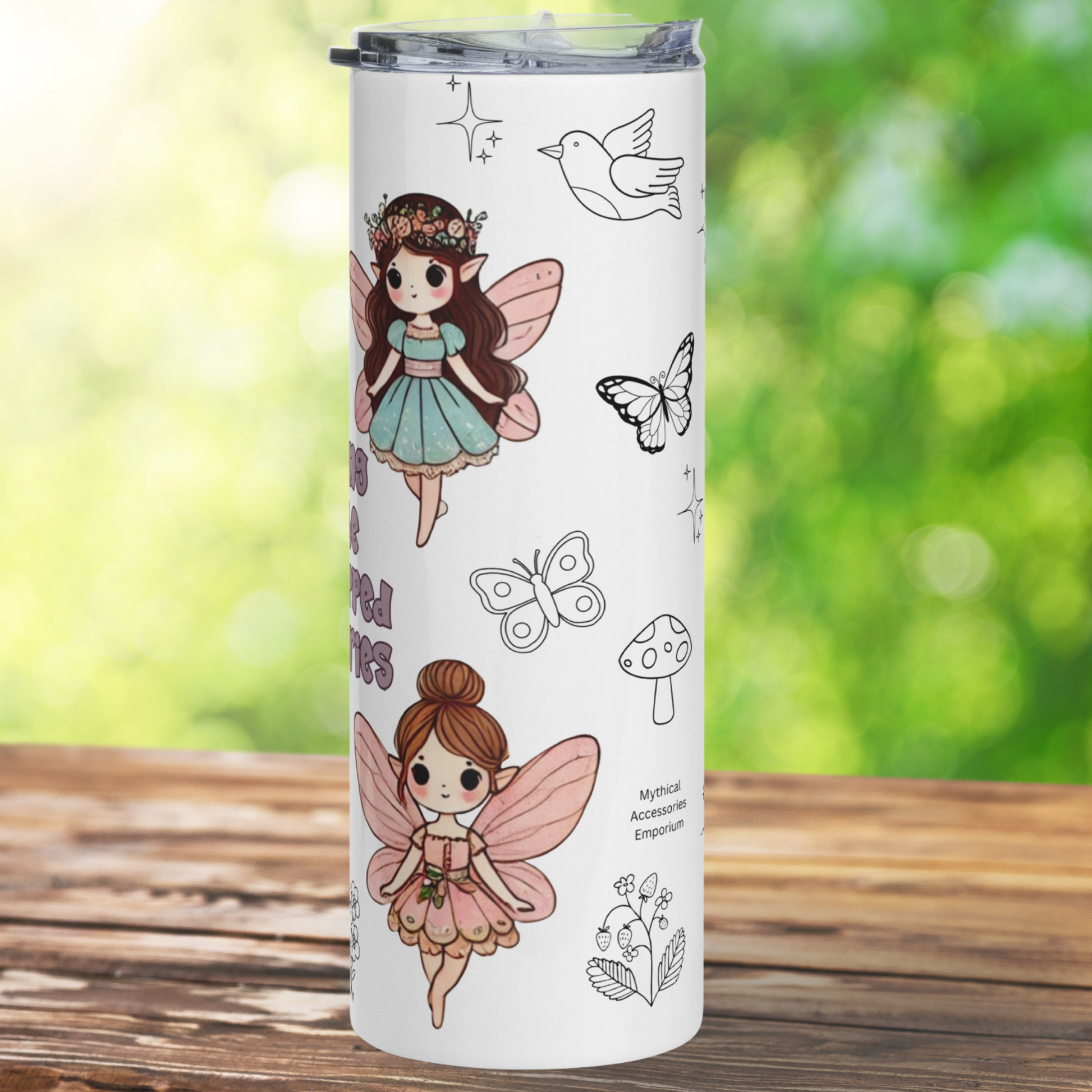 Kidnapped by Fairies 20 oz Stainless Steel Tumbler right side view. On this side in the background you see doodles in black and white of birds, butterflies, mushrooms, and a strawberry plant. At the top is a fairy in a blue poofy dress, pink wings, long flowing brunette hair, and pointed wings, She is standing. At the bottom you see a fairy with auburn hair in a bun, pink wings, and pink poofy dress. She is standing.  Gifts for Readers.