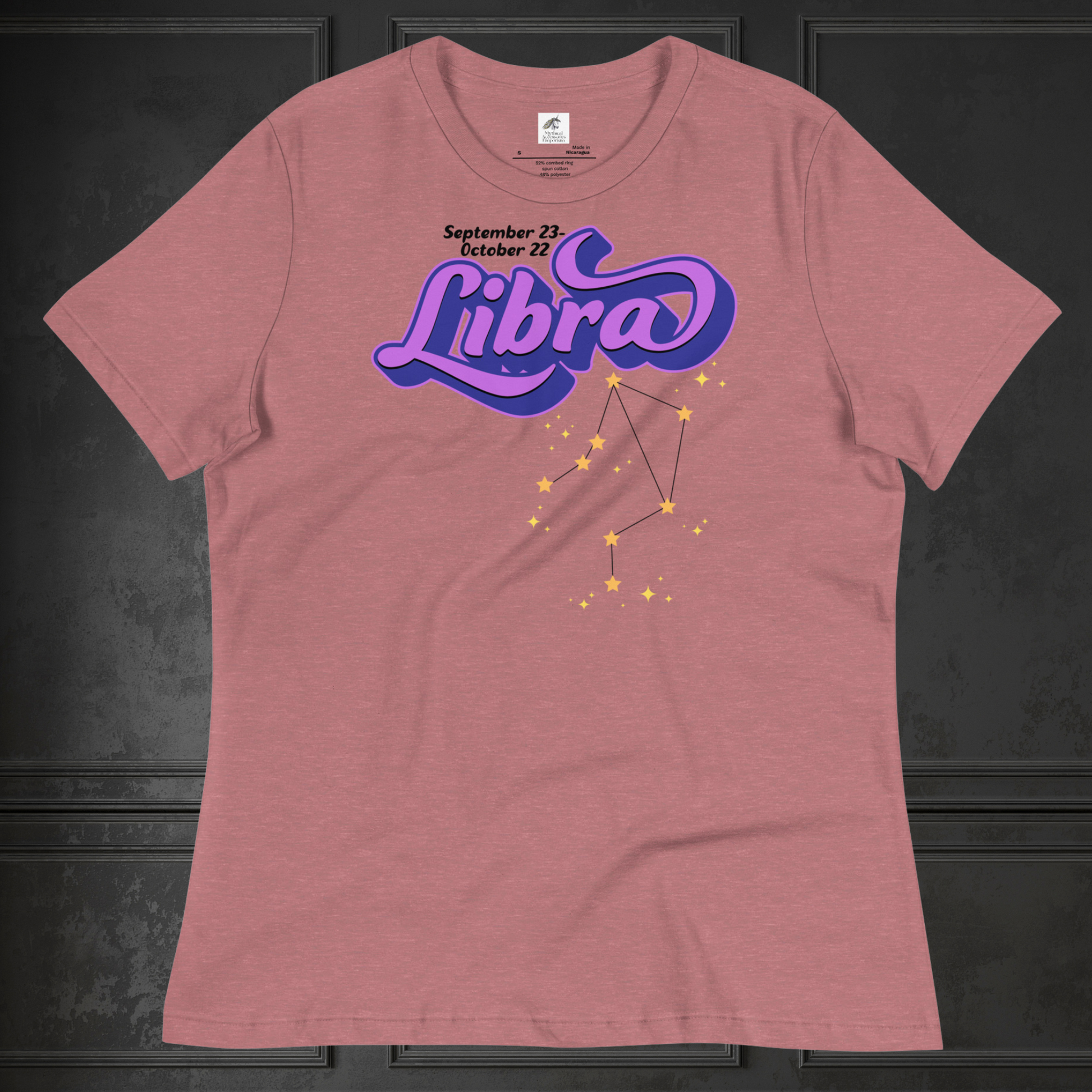 Front view of flat heather mauve women's Libra Tee. This astrology Libra T-Shirt has the word Libra in large purple script shadowed in deep blue for a 3-D effect. Below this it Says September 23-October 22. Under Libra is the zodiac star constellation with yellow stars connected by a black line and lighter yellow smaller stars surrounding this. The perfect October or September Birthday Gift for Her or yourself.