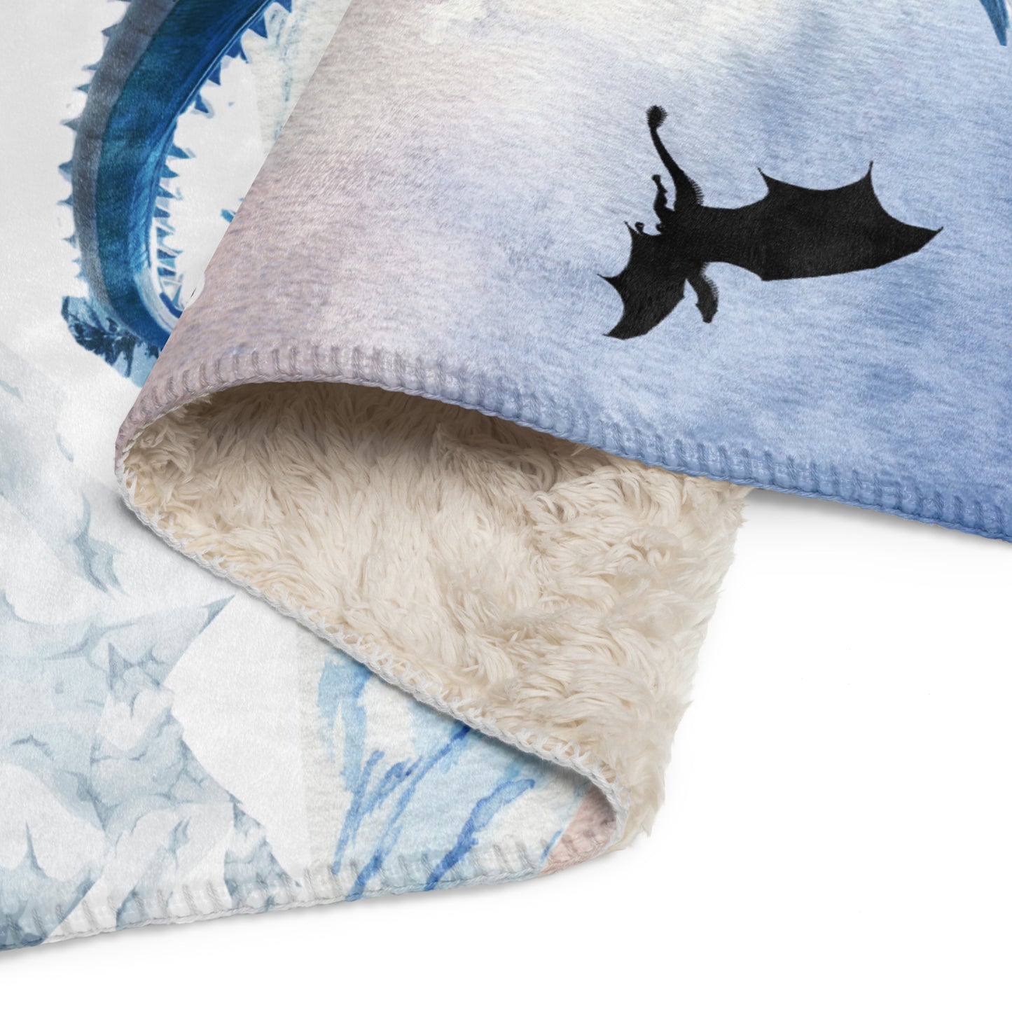 My Spirit Animal Dragon Blanket. Up close view to see the front printed side and folded over to see the natural color sherpa on the back.  Blue Ice Dragon with wings spread standing in front of snow capped mountain range with a dragon silhouette flying above within a blue grey circle. Ice Dragon Fantasy Bookish Gift, Dungeons and Dragons DND Dungeon Master Gift, Fantasy Home Decor