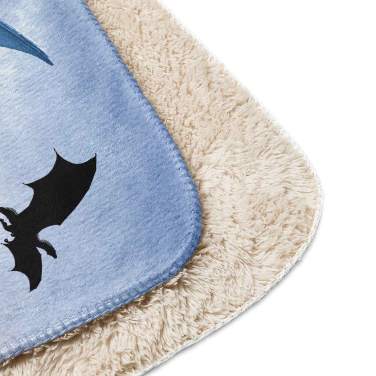 My Spirit Animal Dragon Blanket. Up close view of front folded over to see the sherpa and corner of both sides. Blue Ice Dragon with wings spread standing in front of snow capped mountain range with a dragon silhouette flying above within a blue grey circle. Ice Dragon Fantasy Bookish Gift, Dungeons and Dragons DND Dungeon Master Gift, Fantasy Home Decor