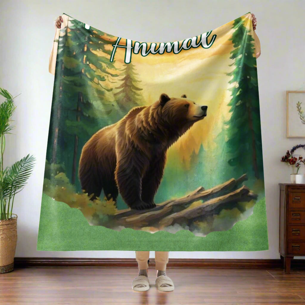 My Spirit Animal bear sherpa blanket.  Front view of 60"x80" held up in the air by model. Folded 1/4 of the way over the hands and hanging down almost to the ankles.  Blanket is perfect for a twin sized bed or as a queen bed throw. Grizzly Bear paused in front of logs walking through the forest framed in a sunset. My Spirit Animal text at the top in white script.