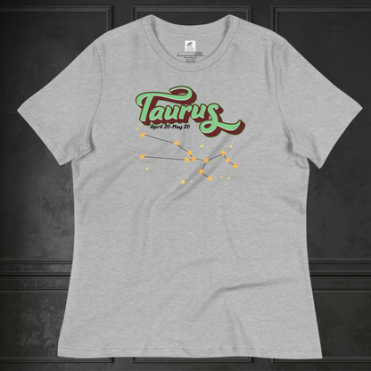 Front view of athletic heather (grey) Taurus Tee laying flat on a black surface. You can see the crew neck collar and short sleeves of the t shirt. This Astrology T-Shirt has the word Taurus in large leaf green script shadowed in deep brown for a 3-D effect. Below this it Says April 20-May 20. At the bottom is the star constellation for Taurus with yellow stars connected by a black line and  smaller stars surrounding the constellation. The perfect April or May Birthday Gift for Her or yourself.