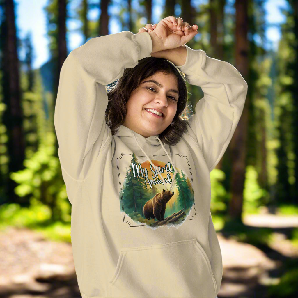 My Spirit Animal bear women's hoodie. Front view model sand hoodie.  Grizzly Bear paused in front of logs walking through the forest framed in a sunset. My Spirit Animal text at the top in white script.