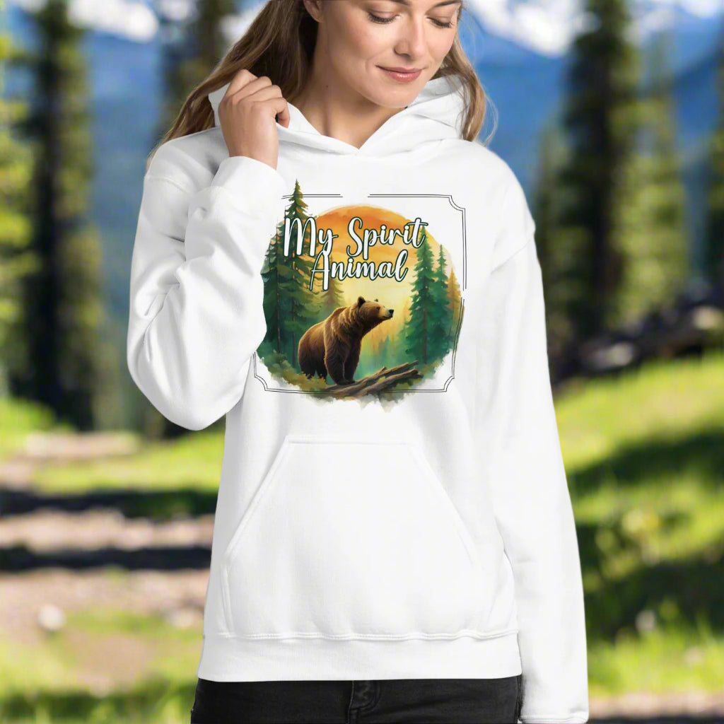 My Spirit Animal bear women's hoodie. Front view model in white hoodie.  Grizzly Bear paused in front of logs walking through the forest framed in a sunset. My Spirit Animal text at the top in white script.