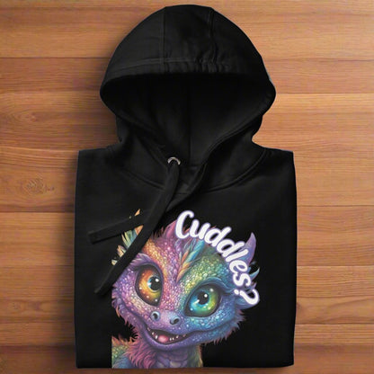 black Men's Hoodie Front View folded on a wooden counter. Purple cross eyed baby dragon. Text above dragon circling head "Cuddles?". 