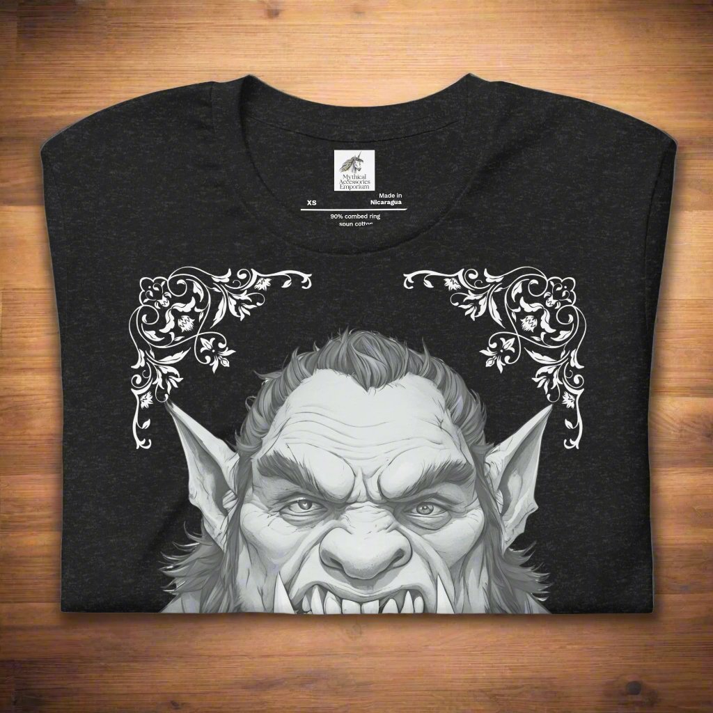 Men's black Orc T-Shirt Front View folded on wooden surface. Orc with tusks and pointed ears. Troll TShirt, Giant TShirt, Ogre Shirt