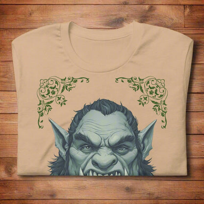 Men's Tan Orc T-Shirt Front View folded on wooden surface. Green skinned orc with tusks and pointed ears.