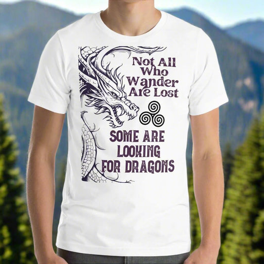 white men’s T-shirt, front view. Right side features a dragon in smoky gray-purple with the Celtic triskele symbol emerging from its nostrils. Text above reads "Not All Who Wander Are Lost," with "Some Are Looking for Dragons" below.