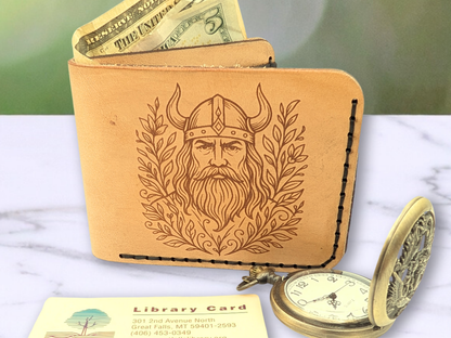Viking Leather Wallet standing up on a white surface with a library card and pocket watch in front. You can see cash peeking up out of the cash compartment. 