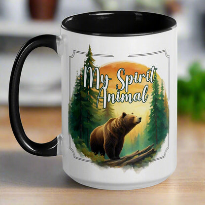 My Spirit Animal bear ceramic mug. black interior and handle with handle to the left.  Grizzly Bear paused in front of logs walking through the forest framed in a sunset. My Spirit Animal text at the top in white script.