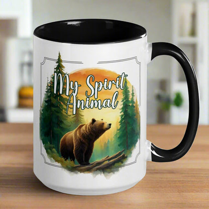 My Spirit Animal bear ceramic mug. Black interior and handle, handle to the right  Grizzly Bear paused in front of logs walking through the forest framed in a sunset. My Spirit Animal text at the top in white script.