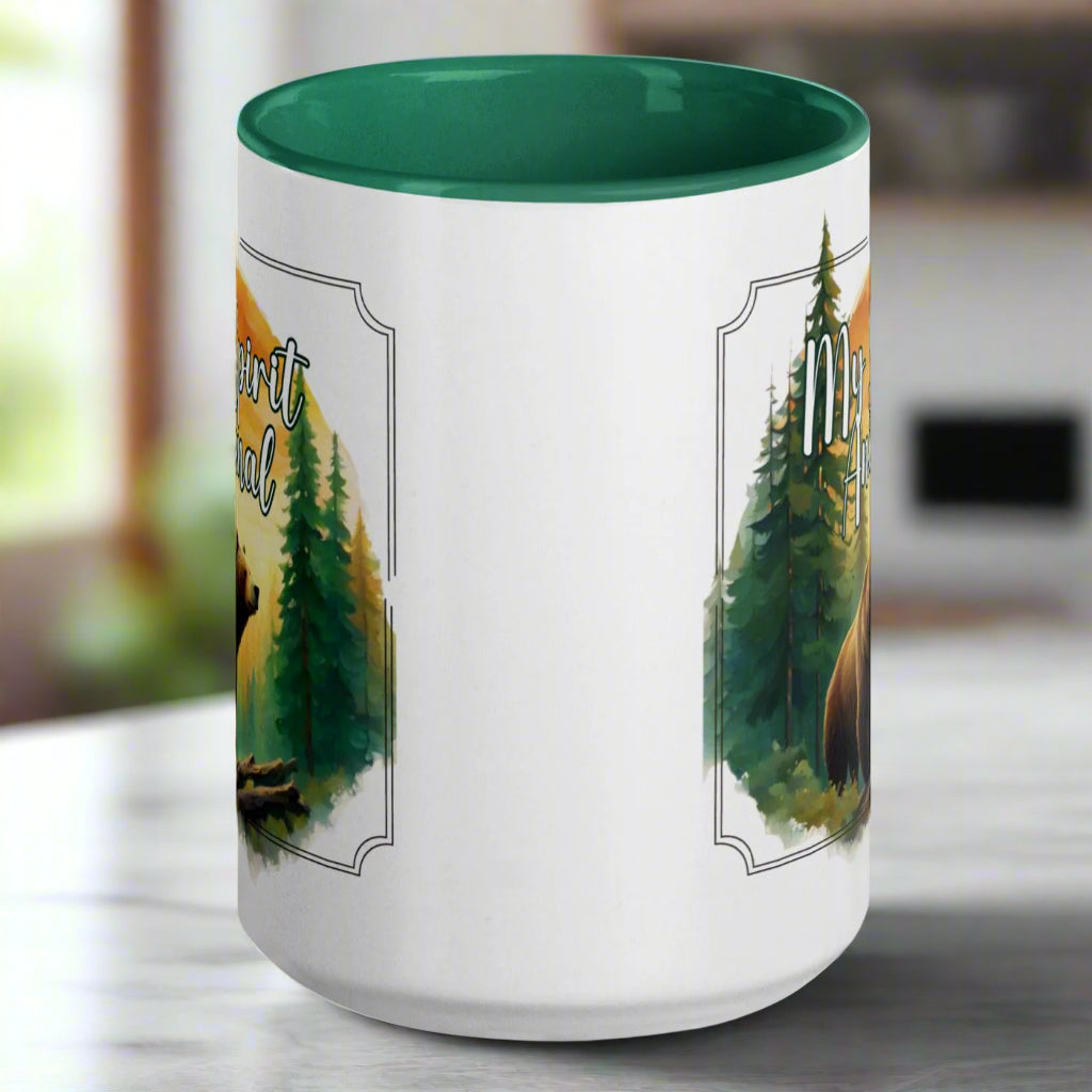 My Spirit Animal bear ceramic mug. Green interior and handle with handle to the back.  Grizzly Bear paused in front of logs walking through the forest framed in a sunset. My Spirit Animal text at the top in white script.