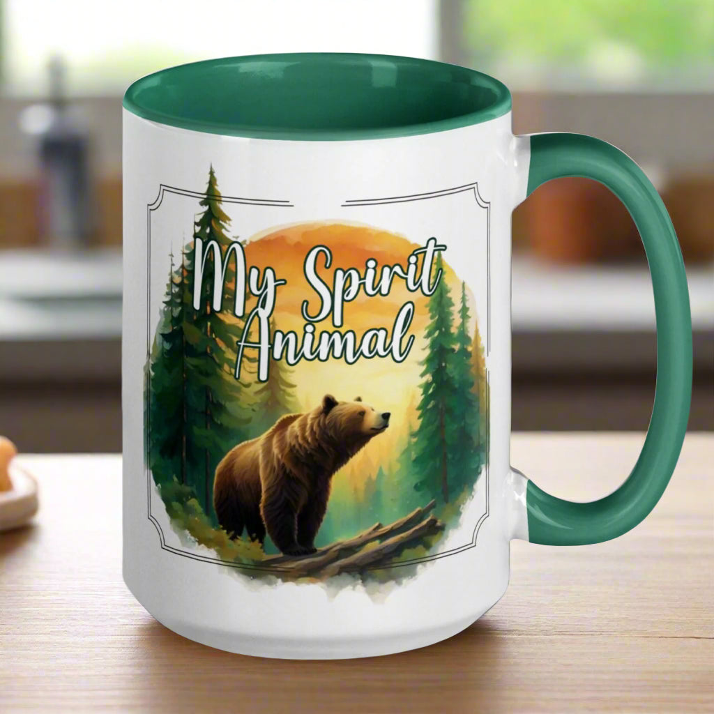 My Spirit Animal bear ceramic mug. Green interior and handle, handle to the right.  Grizzly Bear paused in front of logs walking through the forest framed in a sunset. My Spirit Animal text at the top in white script.