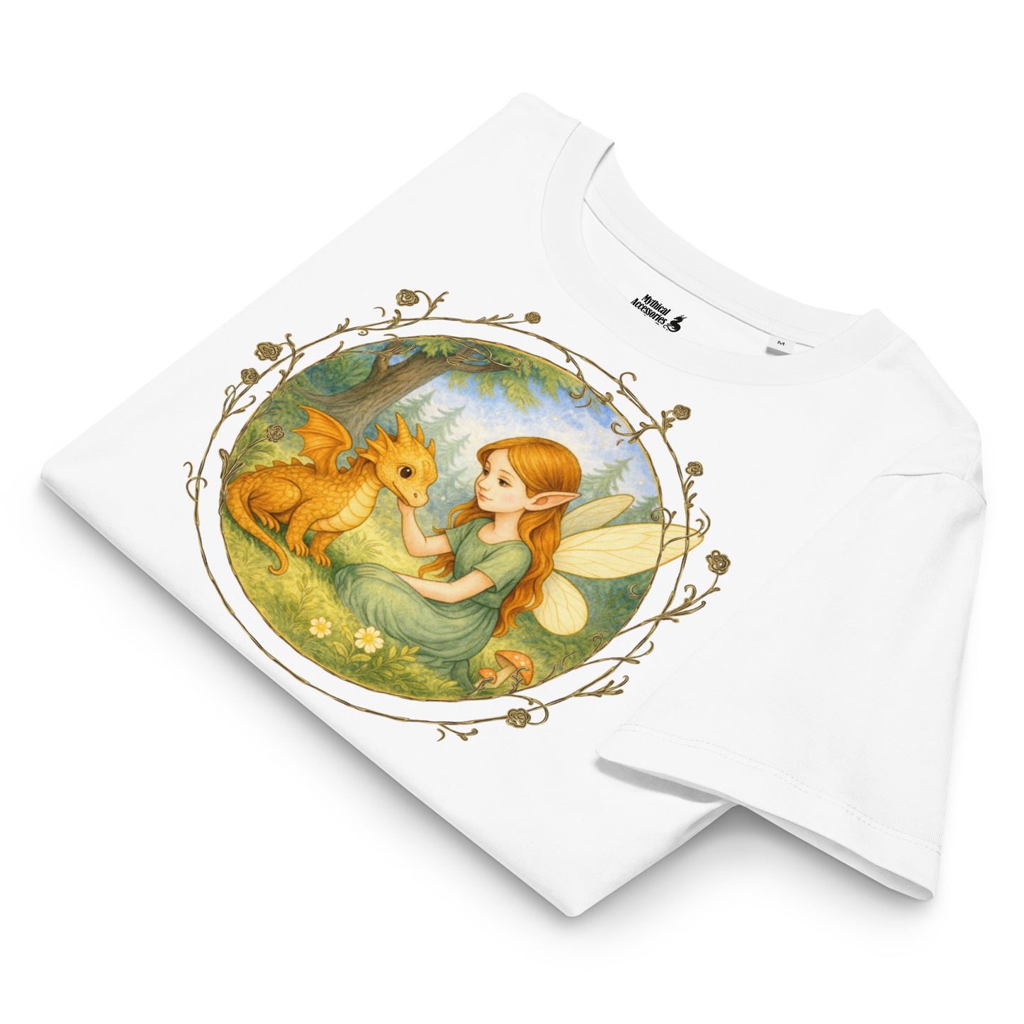 White folded t-shirt with a fantasy graphic. Circle shaped graphic is framed in gold rose vines. A fairy kneels in a forest meadow petting a reddish baby dragon. Fairy is wearing a long green dress and has auburn hair. Insect like wings. 