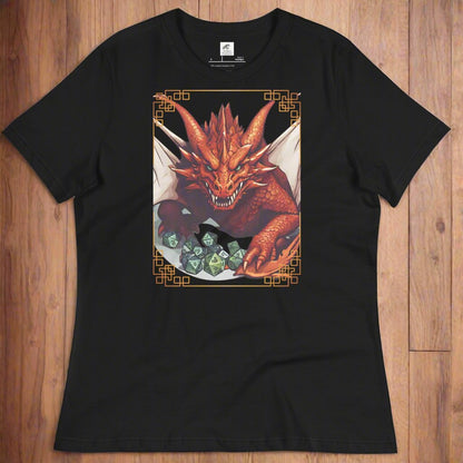 Black Front View Women's  T-Shirt laying flat on wood surface. DND players gift for adventurers. Red Dragon, wings spread, stalking over a pile of D20 and other dice. RPG and Dungeons Masters