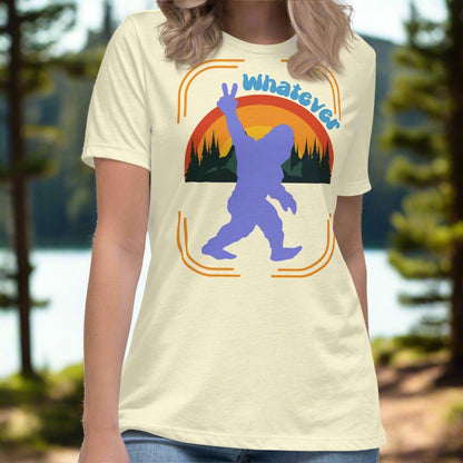 Citron (light yellow) Sasquatch Women's T-Shirt. Big Foot in periwinkle against a rainbow and mountains showing a peace sign with text Whatever. Bigfoot Yeti Women's Tee