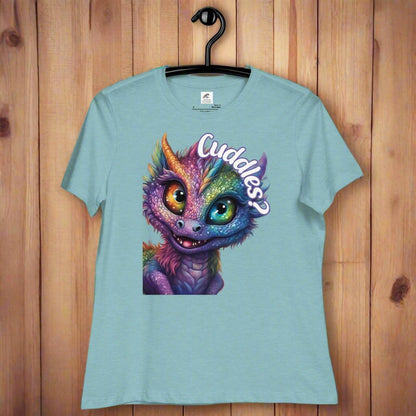 heather blue lagoon Dragon Cuddles Front View Women's T-Shirt on a hanger. Whimsical purple iridescent  dragon looking up at the word Cuddles? above his head