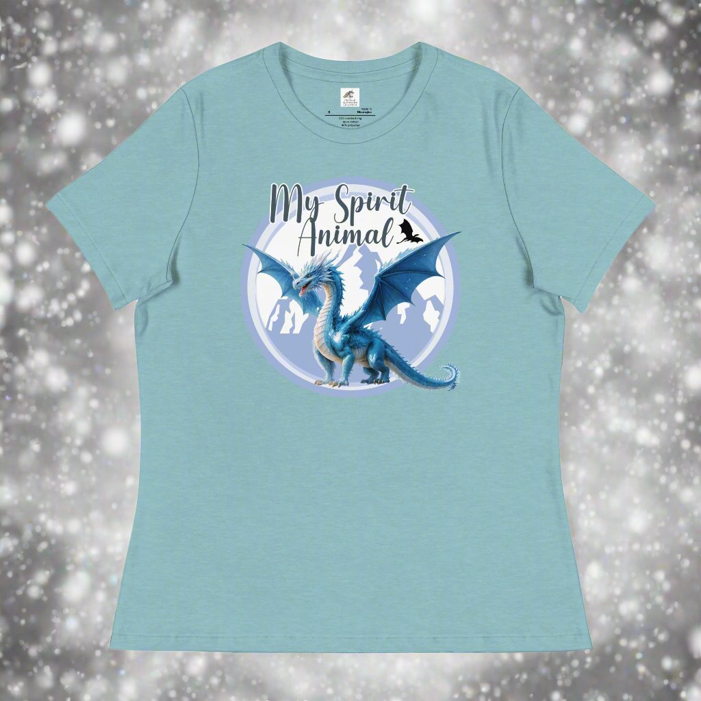 My Spirit Animal Dragon Women's Graphic Tee, front view of flat blue lagoon shirt, Blue Ice Dragon with wings spread standing in front of snow capped mountain range with a dragon silhouette flying above within a blue grey circle