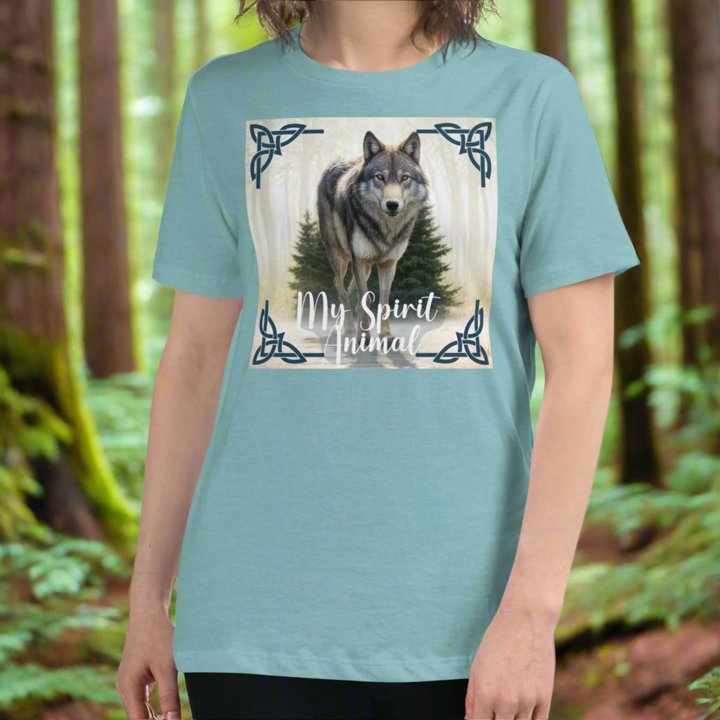 Wolf My Spirit Animal Women's T-Shirt. Front view in heather blue lagoon. A grey wolf gazes at you from the forest bordered in Celtic knots. Timber Wolf Graphic Tee Shamanic Totem Animal, Mythical Accessories Emporium.