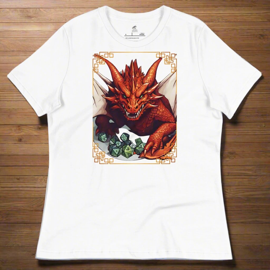 white Front View Women's  T-Shirt laying on a wooden surface. DND players gift for adventurers. Red Dragon, wings spread, stalking over a pile of D20 and other dice. RPG and Dungeons Masters