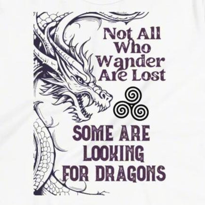 white, Front View close up view of the graphic, Women's T-Shirt. Right side is bordered a dragon in a grey purple. Looking like smoke coming from the dragons nostrils is the Celtic symbol triskele or the triple circle. Above this it says Not All Who Wander Are Lost. Below this it says Some Are Looking for Dragons.