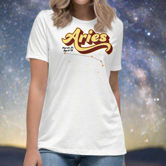 Woman wearing a white t-shirt facing forward. On the top is the word Aries in light yellow lined with maroon. Under the A are the dates March 21-April 19. Below his is the constellation Aries in bright yellow orange stars connected with a black line. Aries constellation zodiac astrology sign.